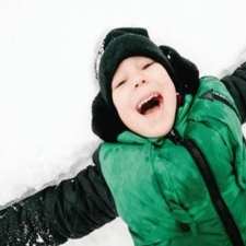 boy in snow in green vest