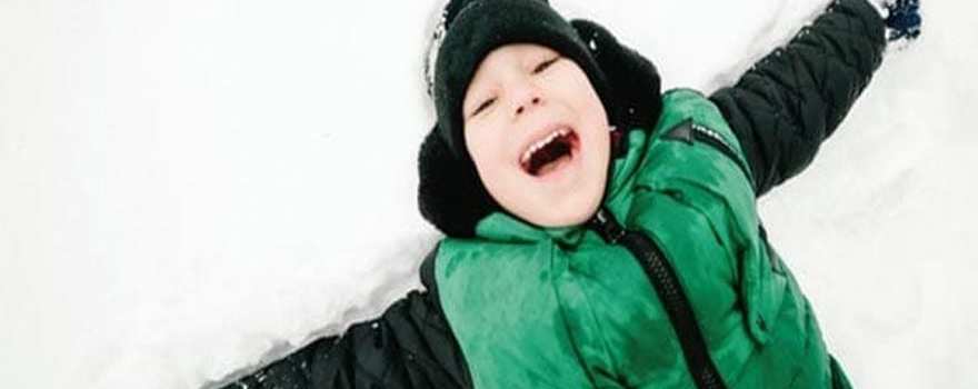 boy in snow in green vest