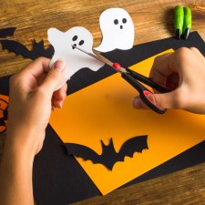 Hand's holding scissors cutting out Halloween images.