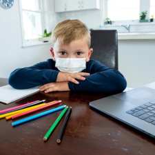 kid in face mask at homework station