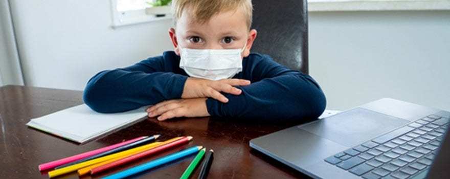 kid in face mask at homework station