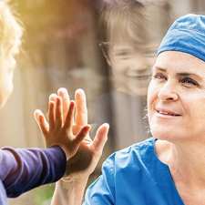 nurse and kid make contact through glass