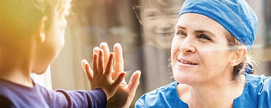 nurse and kid make contact through glass