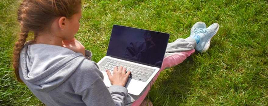 girl using laptop in grass