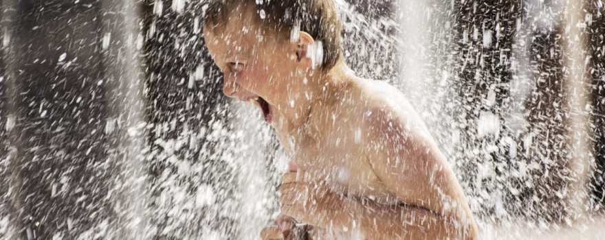 kid playing in sprinkler