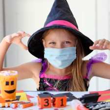 Girl with mask wearing witch costume having Halloween fun