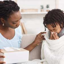 Sick child blows nose next to mom