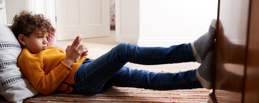 kid on floor looking at phone