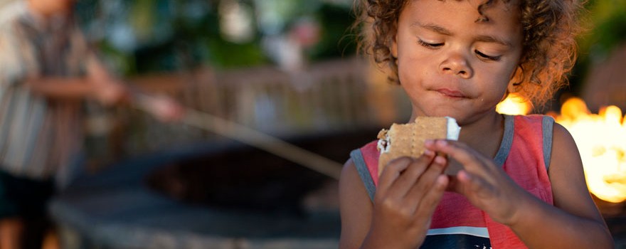 boy eating s'mores and camping