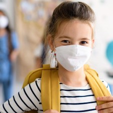 cute elementary school girl in classroom wearing mask