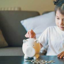 young girl saving money in piggy bank