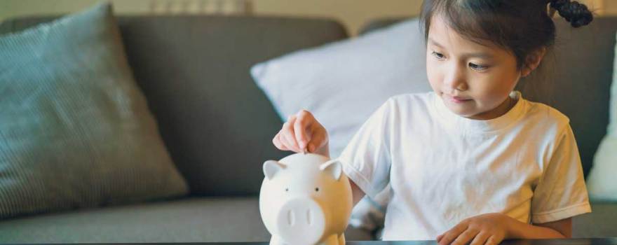 young girl saving money in piggy bank