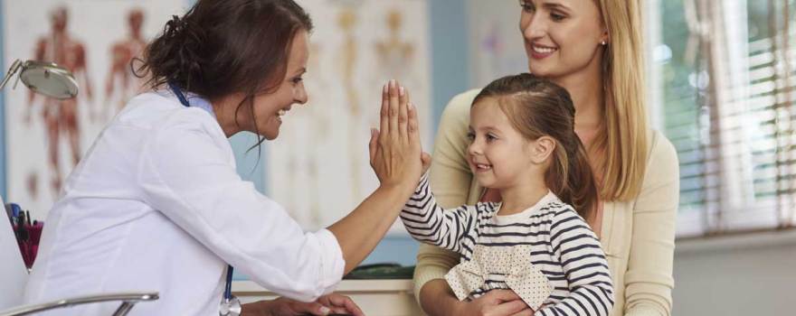 child giving pediatrician high-five while parent asks questions