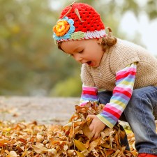 Little girl playing in fall leaves