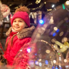 girl in winter coat surrounded by holiday ornaments