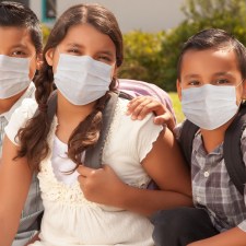 kids in schoolbags wearing masks