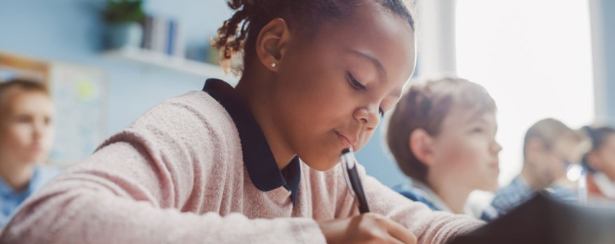 young girl writing in classroom