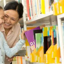 child and mother looking at books at public library