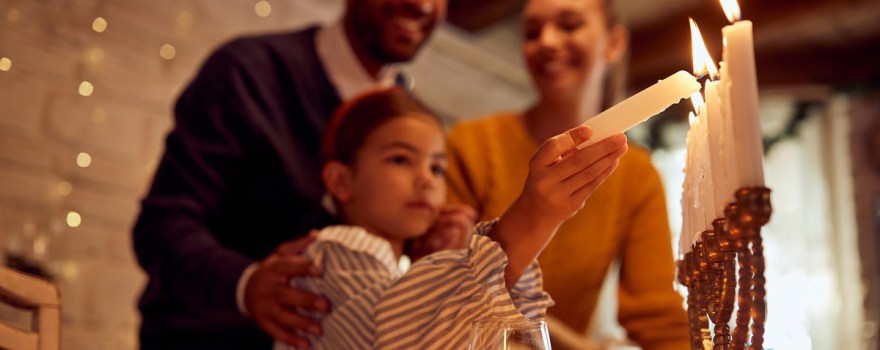 Jewish family lights a menorah during Hanukkah