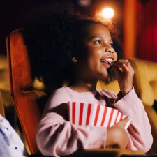 Kids eat popcorn and watch a movie at the movie theater