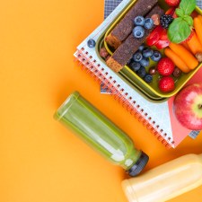 a lunchbox of sliced fruit on top of notebooks