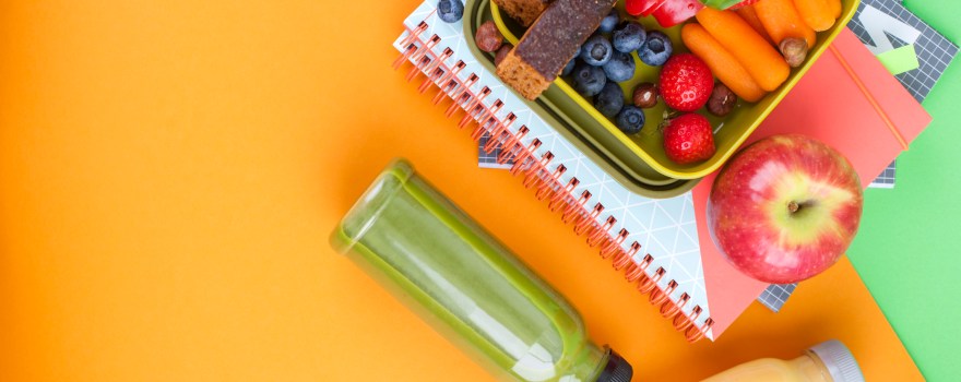 a lunchbox of sliced fruit on top of notebooks