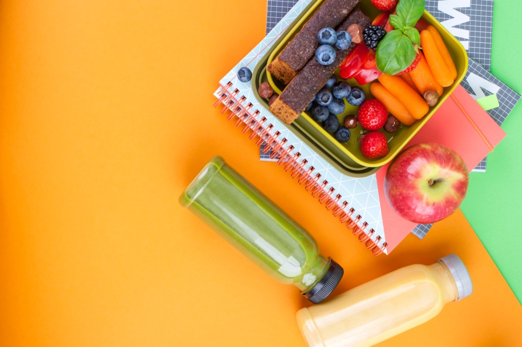 a lunchbox of sliced fruit on top of notebooks