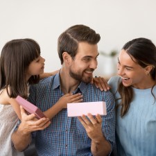 dad holding a gift with wife and daughter next to him