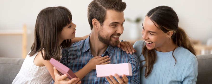 dad holding a gift with wife and daughter next to him