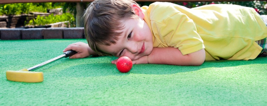 Young boy playing mini golf