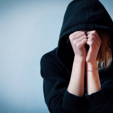 Young girl hiding her face under hooded sweatshirt