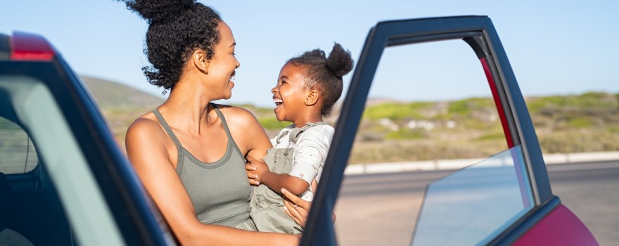 mother and young daughter next to a car