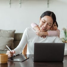 Family caregiver with a young child at a laptop.