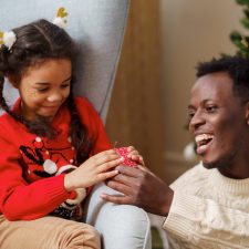 Father giving his daughter a holiday gift.