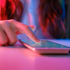 Hand of teen girl scrolling on a phone.