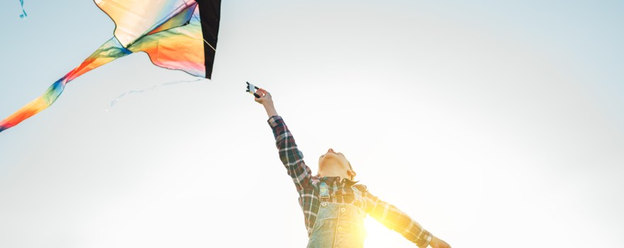 Child flying a kite outdoors on a sunny day. Many kite festivals in New York and New Jersey let people fly kites.