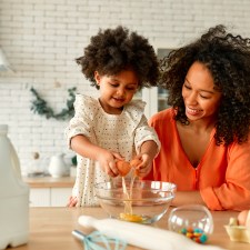 Parent and child preparing food together in a kitchen.