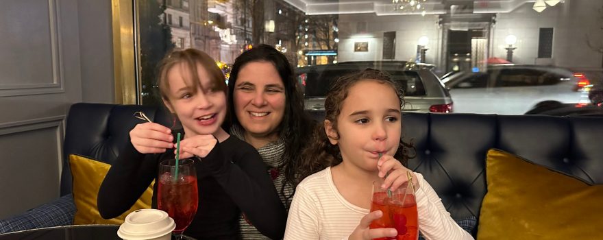 A mom who is nominated in a Super Mom contest sitting in a restaurant with her two daughters.