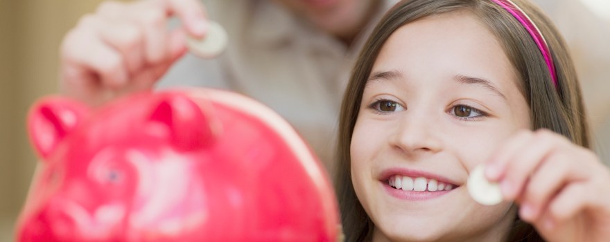 Father and daughter putting coins in a piggie bank, which can be a way of teaching kids financial literacy.