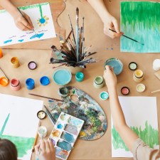 Kids painting crafts on a table, which can be an activity at stores offering free or cheap classes for kids.