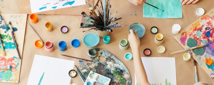 Kids painting crafts on a table, which can be an activity at stores offering free or cheap classes for kids.