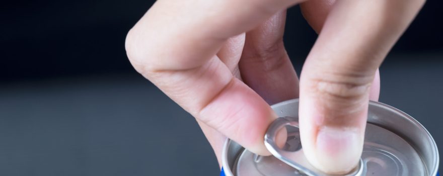 A person's hand opening a can. Prime energy drink is available in a similar can