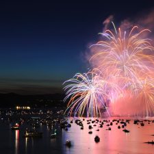 boats on the water at night with fireworks in the sky