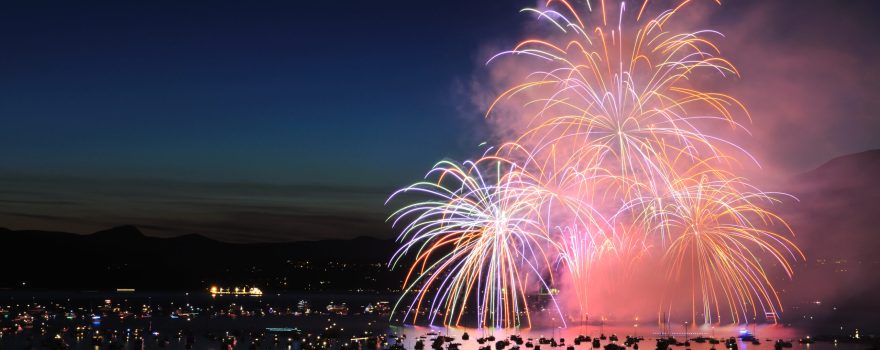 boats on the water at night with fireworks in the sky