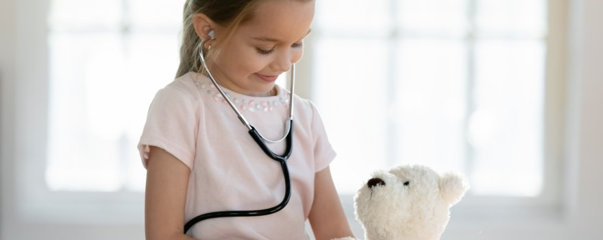 child using a stethoscope on a teddy bear; now is a great time to make appointments for back-to-school checkups