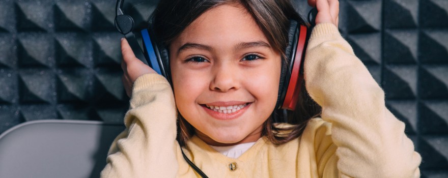 a little girl wearing headphones during a hearing test, which is a way of detecting and preventing hearing loss in children