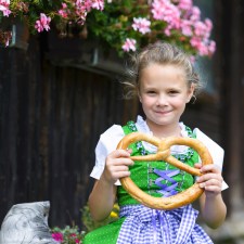 little girl holding a pretzel at a festival similar to celebrations of Oktoberfest on Staten Island and nearby