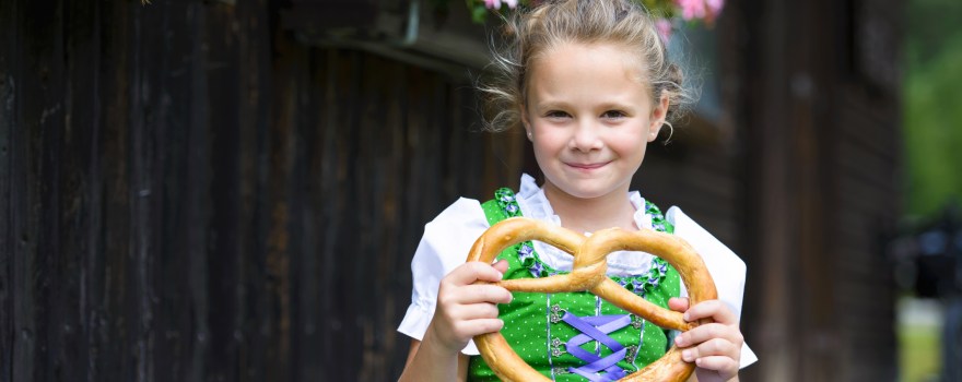 little girl holding a pretzel at a festival similar to celebrations of Oktoberfest on Staten Island and nearby