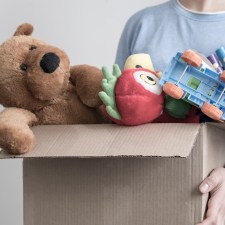 A person holding a donation box of toys, which is one idea for what to do with your kids’ old toys