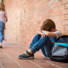 Young boy in school, looking withdrawn, which is one of several signs of bullying